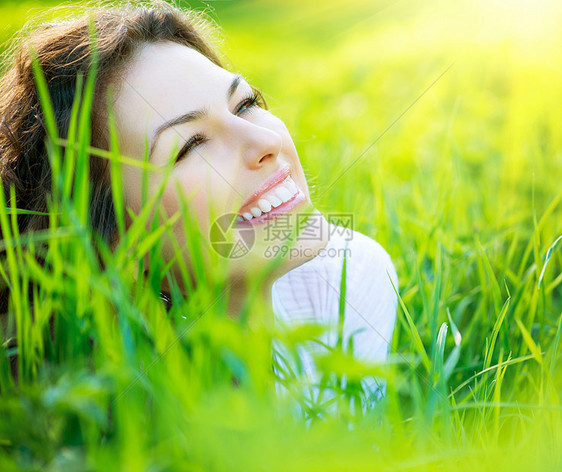 美丽的春春女青年外出门享受大自然草地太阳环境过敏女士牙齿自由说谎微笑农村图片
