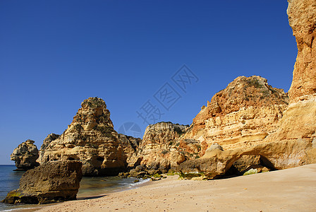 海滩沙滩岩石橙子悬崖蓝色镜子日落砂岩反射旅行地标图片
