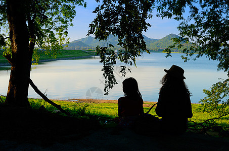 两姐妹的休丽花坐在水库风景中放松图片