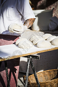 贝克在中世纪集市做工匠面包面粉桌子木板谷物苏打棒子蓝色早餐店铺食物背景图片