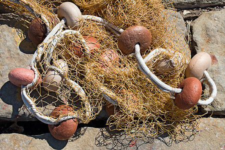 带有罗佩斯和浮游鱼的渔网地面渔业石头橙子绳索摄影渔夫材料港口手工图片