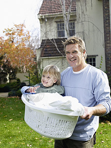 父亲带男孩(3-4)在院子里洗衣篮里图片