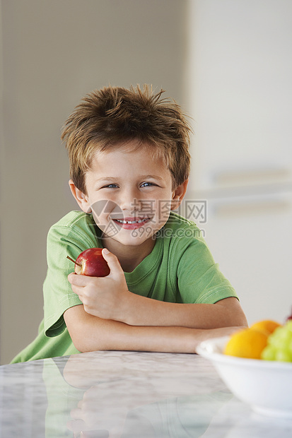 在厨房里拿着苹果的年轻男孩图片