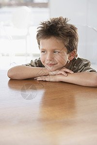 带着头的年轻男孩双手在桌子上躺着图片
