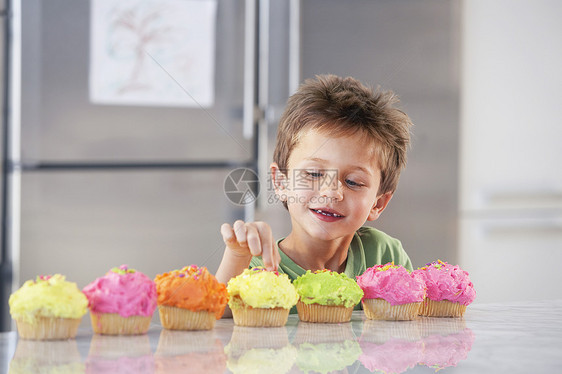 年轻男孩在厨房里摘蛋糕的装饰品图片