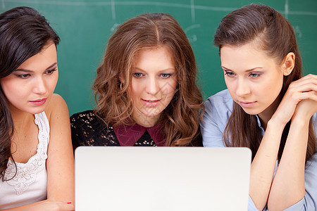 三个学生和一个笔记本教育技术房间说谎白色微笑照片女性互联网电脑图片