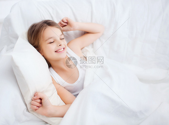 在家床上醒来时笑着微笑的女童青少年唤醒枕头毯子休息说谎睡眠苏醒女孩寝具图片