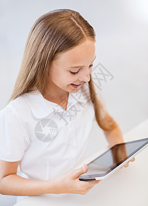 学校里带着平板电脑微笑的女孩学生小学生青春期课堂电子书学习童年上网桌子药片图片