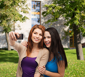 两个带着智能手机的笑笑青少年朋友们电话相机女性细胞互联网照片娱乐技术青年图片