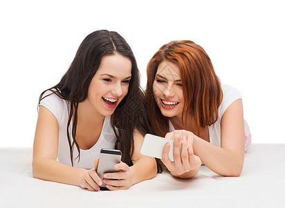 两个带着智能手机的笑笑青少年社会娱乐闺蜜电话白色友谊朋友们学生视频乐趣图片