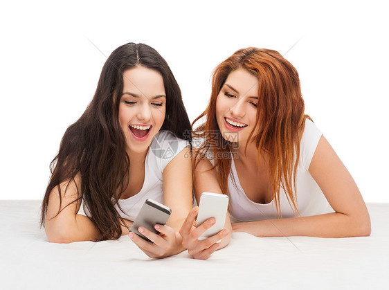两个带着智能手机的笑笑青少年闺蜜互联网技术游戏电话乐趣白色朋友们学生细胞图片