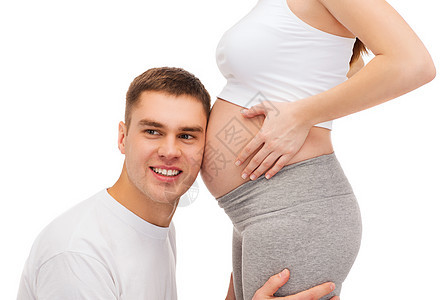 快乐的父亲听着他怀孕妻子的肚子母性婴儿男性微笑产妇女士男人孩子父母爸爸图片
