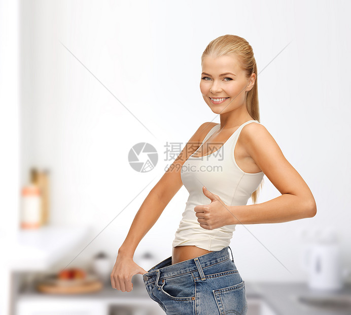 穿着大裤子的运动妇女女孩微笑节食福利损失重量牛仔裤腰围厨房女性图片