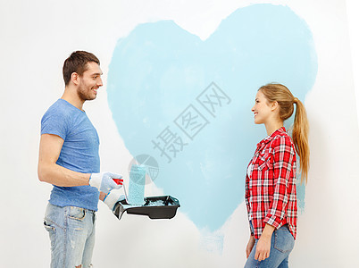 一对在墙上画着大心的情侣手套蓝色房子滚筒画笔画家装潢夫妻团队绘画图片