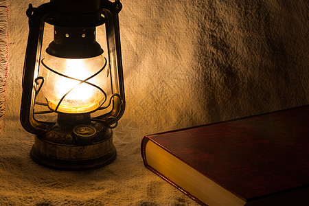 用旧生锈的灯笼和一本书烧伤玻璃蜡烛火焰煤油艺术黄铜阅读古董红色图片