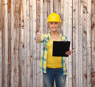 带着剪贴板戴头盔的笑着女人齿轮木头工作承包商栅栏职员维修工程师成人女性图片