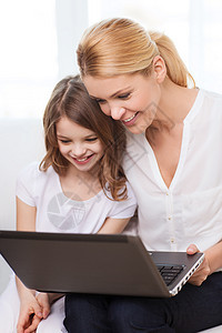 在家里拿着笔记本电脑的微笑的母亲和小女孩房间妈妈女性家庭父母孩子乐趣幸福青春期技术图片