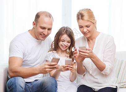 父母和家里有智能手机的小女孩的父母技术互联网母亲男人女儿女士妈妈青少年童年青春期图片