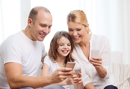 父母和家里有智能手机的小女孩的父母家庭母亲互联网男人妈妈成人电话青少年幸福女士图片