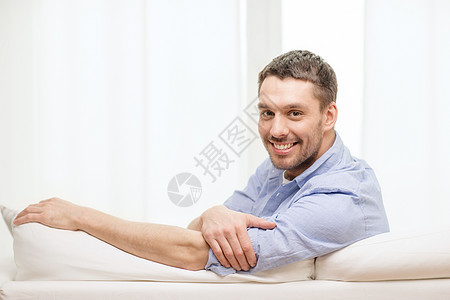坐在家里沙发上笑着笑着的男人思维房子拉丁长椅房间幸福闲暇福利男性成人图片