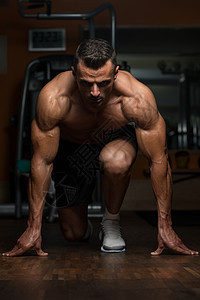 身高强壮的男子跪在地板上重量起跑线短跑运动能力运动员服装身体跑步影棚图片