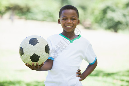 小男孩在公园里拿着橄榄球 微笑着看镜头童年快乐黑色环境闲暇绿地农村足球活动阳光图片