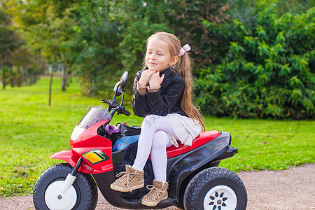 穿着皮夹克的可爱小女孩 坐在玩具摩托车上图片
