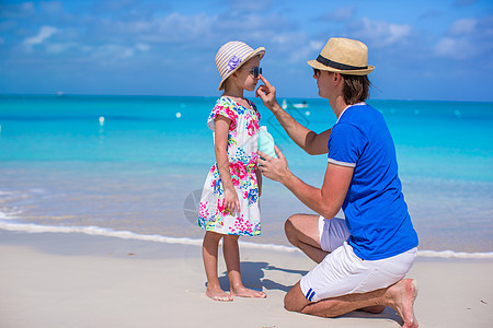 父亲在他女儿鼻子上涂防晒霜膏海洋太阳微笑男人紫外线洗剂喜悦假期护理海滩图片