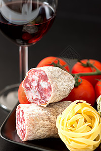 番茄意大利面和红葡萄酒的盘子上的腊肠图片