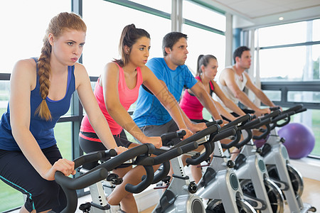 下定决心的人在旋转课上打工健身室身体女性健身房器材俱乐部男人自行车女士健身图片