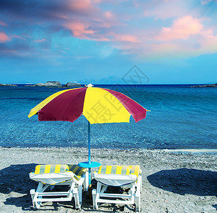 美丽的沙滩上挂着草伞的多彩海滩椅晴天假期阳伞海岸热带小屋椅子旅行海洋稻草图片
