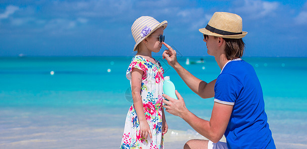 父亲在他女儿鼻子上涂防晒霜膏太阳海滩喜悦皮肤童年女性棕褐色奶油晴天假期图片