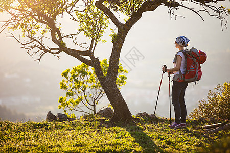 女性登山者站在悬崖上享受风景背包太阳远足场景女士女孩游客冒险旅行岩石图片