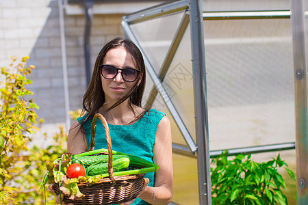 在温室里拿着一篮绿菜和洋葱的年轻女子花园收成农场收获园艺女孩食物国家农民篮子图片