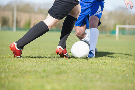 足球运动员在球投出时追击球蓝天竞赛袜子男生抢断播放器男人齿轮活动挑战图片