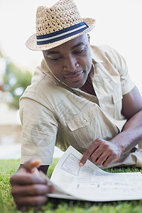 微笑的男人在他的花园阅读报纸上放松了一下男人花园休闲黑色手机阅读男性帽子闲暇服装图片