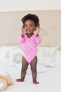 穿粉红婴儿裤的小女孩宝宝 站在床上玩具粉色家庭卧室女性幸福快乐动物棉被婴儿图片