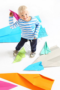 一个小男孩手里握着一架纸机乐趣艺术塑像专注飞行员控制投掷航空力量闲暇图片