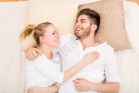 床上快乐的年轻夫妇微笑男人成人丈夫拥抱感情幸福女士卧室亲热图片