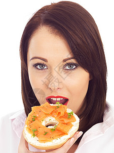 食用烟熏鲑鱼和奶油奶酪面包圈的年轻妇女女士熏制午餐治愈食物冒充白色女性黑发小吃背景图片