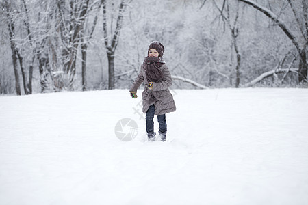 快乐的小女孩跑在雪上蒙着圆珠彩的背景下小姑娘针织冬装衣服夹克公园女性童年乐趣雪堆图片
