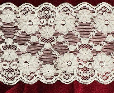 红色派边织物上的蕾丝装饰花边缝纫材料边框丝绸背景图片