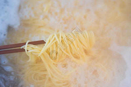 煮着的意面家庭食物面条蒸汽厨房文化筷子烹饪平底锅背景图片