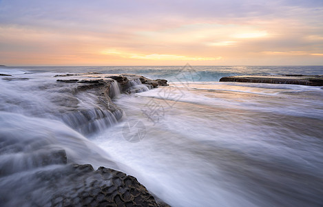 快速波浪和日出Curl curl 岩石架背景