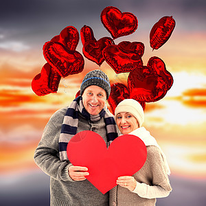 喜悦的成熟情侣在冬衣中装着红心的复合形象保暖橙子天空阳光夫妻男人绘图帽子紫色羊毛图片