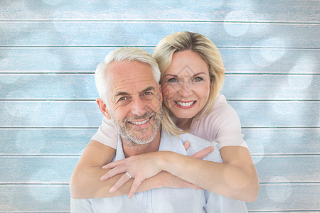 微笑的情侣拥抱和观看相机的复合图像丈夫妻子圆圈金发女郎男性木板女性蓝色亲密感婚姻图片