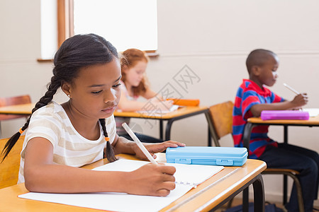 在课堂桌上写字的可爱学生学习学校小学生桌子童年女孩椅子知识同学们早教图片