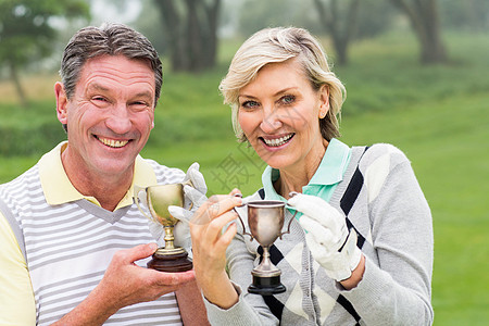 快乐高尔夫夫妇的奖杯闲暇运动员成功休闲夫妻男性微笑女性快乐优胜者图片