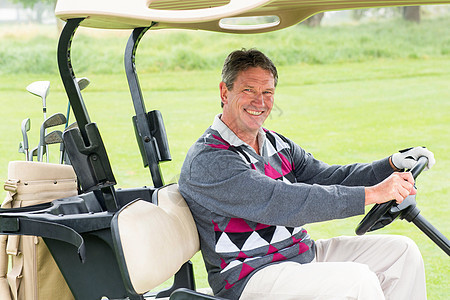 快乐的高尔夫球手驾驶他的高尔夫蜂鸣在相机上微笑假期服装男人晴天运动员方向盘男性闲暇活动休闲图片