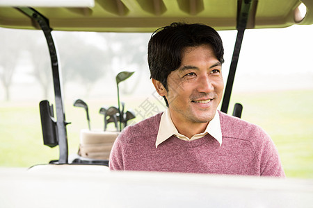 快乐的高尔夫球手驾驶他的高尔夫鼓男性驾驶多云活动休闲运动员高尔夫球绿色假期服装图片